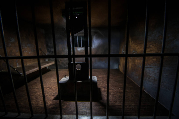 Teloituksen käsite. Kuolemanrangaistus giljotiini pienoiskoossa vanhan vankilan sisällä. Vanhat sellilukot. Luova taideteos koristelu. Kauhu näkymä giljotiini mittakaavassa malli pimeässä - Valokuva, kuva