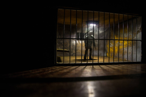 Man in prison man behind bars concept. Old dirty grunge prison miniature. Dark prison interior creative decoration. Selective focus - Photo, image