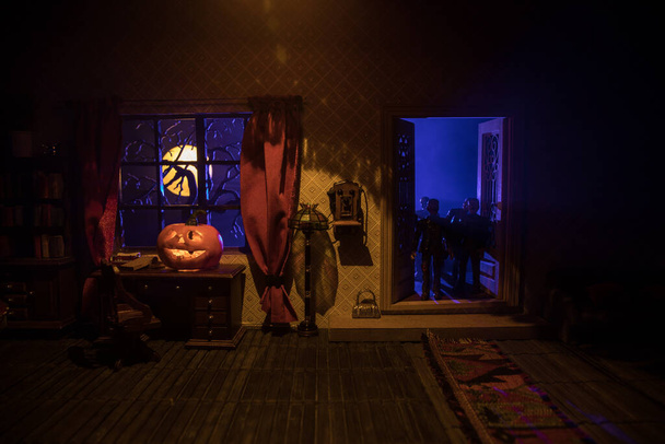 Halloween kauhu käsite hehkuva kurpitsa. Realistinen nukkekodin olohuone huonekaluilla, ovella ja ikkunalla yöllä. Pelottavia zombeja ulkona. Valikoiva painopiste. - Valokuva, kuva
