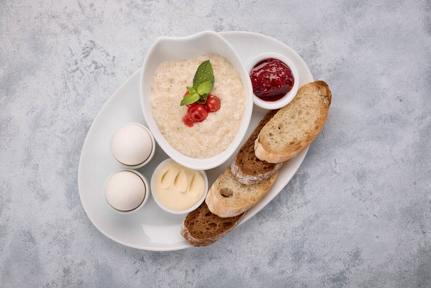 Frühstück aus Brei, Butter, gekochten Eiern, Marmelade und Toast, Croutons, auf weißem Hintergrund - Foto, Bild