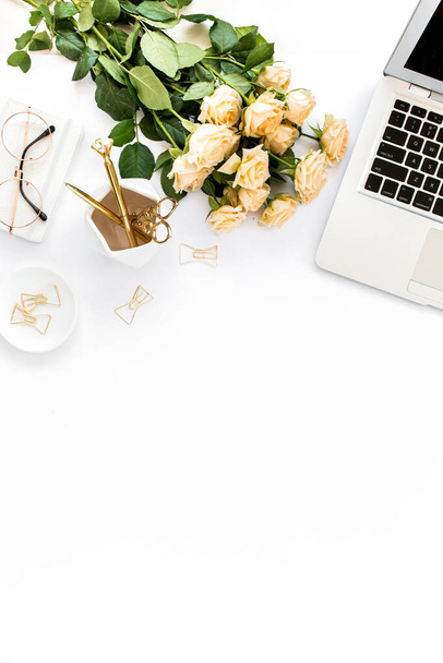 Γυναικείος χώρος εργασίας με laptop, τριαντάφυλλα λουλούδια, χρυσά αξεσουάρ, ημερολόγιο, υπολογιστή, γυαλιά σε λευκό φόντο. Επίπεδη θέση γραφείου γυναικών. Άνω όψη - Φωτογραφία, εικόνα