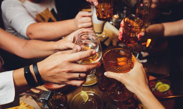 Close up shot of group of people clinking glasses with wine or champagne in front of bokeh background. older people hands. - Fotoğraf, Görsel