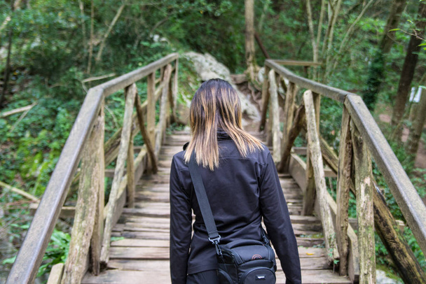 junges Mädchen überquert Holzbrücke im Wald. - Foto, Bild