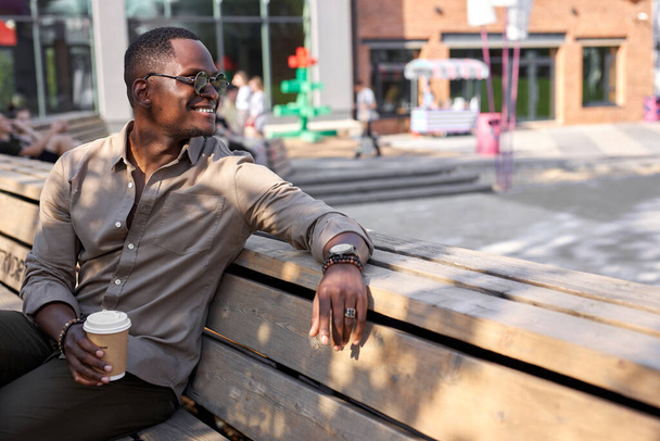 gut aussehender afroamerikanischer Mann ruht sich im Freien aus, trinkt Kaffee - Foto, Bild