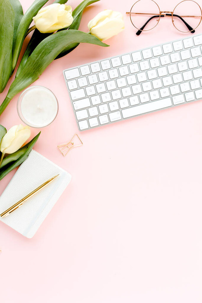 Espaço de trabalho feminino com computador, buquê de flores de tulipa, acessórios dourados, diário, em fundo rosa. Mesa de escritório de mulheres leigas plana. Vista superior - Foto, Imagem