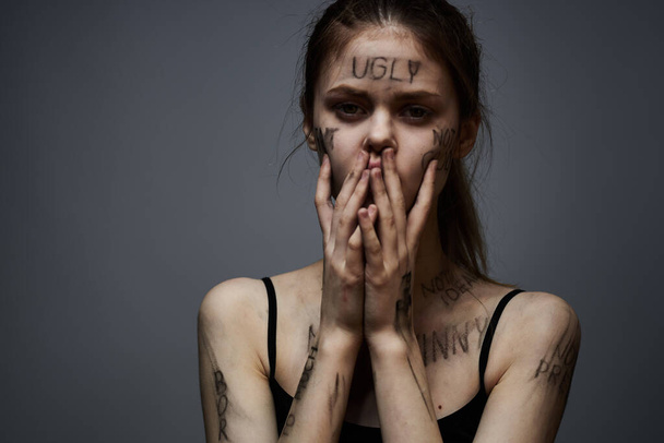 mujer molesta con escritura ofensiva en su cuerpo sobre fondo gris tocándose con las manos vista recortada - Foto, Imagen