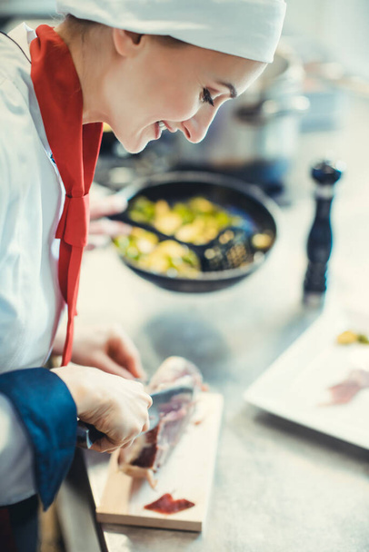 Chef cook in fancy restaurant kitchen slicing ham for a dish - Foto, imagen