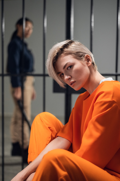 Egy fiatal, piercinges szőke nő börtönben van számítógépes bűnözés miatt. Főportré egy börtöncella hátteréről. - Fotó, kép
