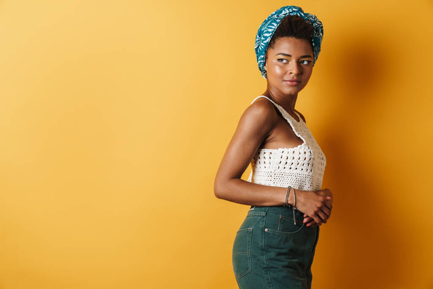 Image of pleased african american woman posing and looking aside isolated yellow background - Photo, Image