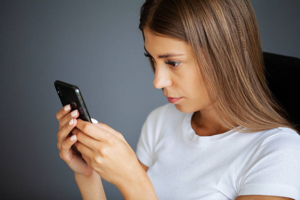 Женщина держит смартфон, печатает сообщения, общается с друзьями в социальных сетях - Фото, изображение
