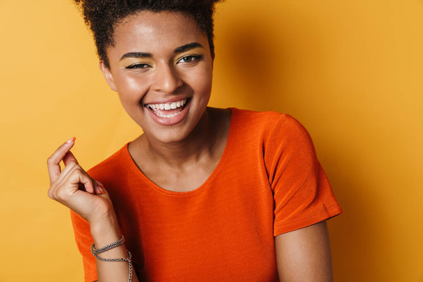 Image of cheerful african american woman posing and laughing on camera isolated yellow background - Zdjęcie, obraz