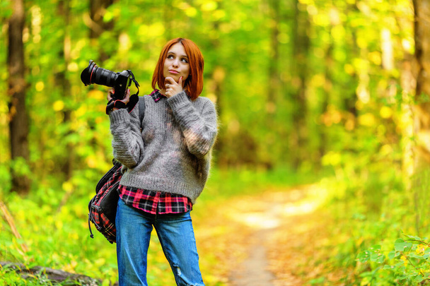 Wistful woman photographer in autumn forest. Shallow dof - Фото, изображение