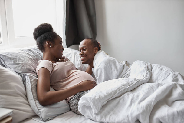 happy afroamerican married couple lie on bed - Zdjęcie, obraz