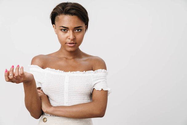 Image of young african american woman holding copyspace and looking at camera isolated over white background - Zdjęcie, obraz