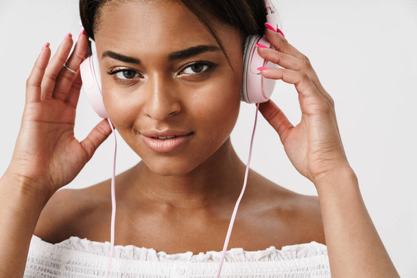 Image of young african american woman posing and using headphones isolated over whited background - Photo, Image