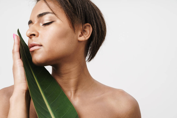 Image of shirtless african american woman posing with green leaf isolated over white background - Foto, immagini