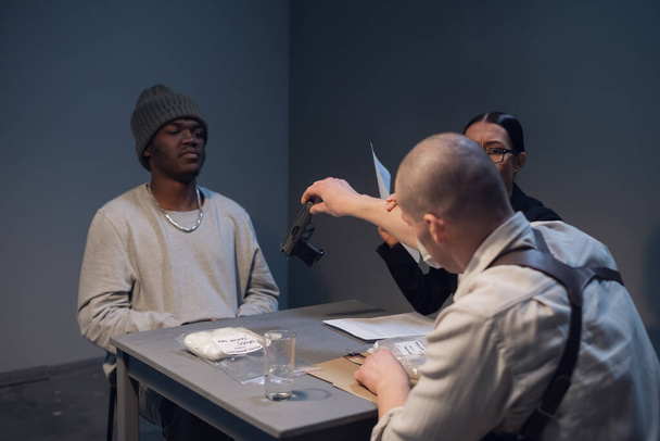 Una hermosa abogada con gafas se familiariza con la evidencia durante el interrogatorio de su cliente, un drogadicto negro. - Foto, imagen