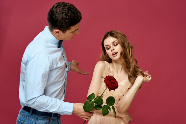 enamored man and woman with a red flower on a pink background hug each other Copy Space - Foto, Imagem