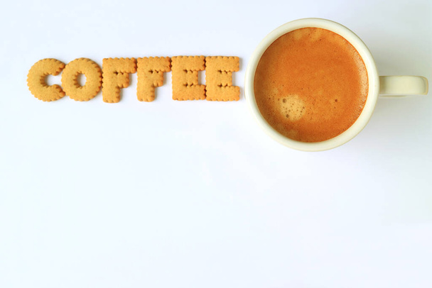Vista superior de galletas en forma de alfabeto, deletreando la palabra CAFÉ con una taza de café sobre fondo blanco con espacio libre para texto y diseño - Foto, imagen