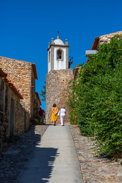 Figueira de Castelo Rodrigo, Portugali - 08 23 2020: Näkymä polulle, jolla turistit kävelevät keskiaikaisten linnoituskylän tornien ja keskiaikaisten rakennusten sisäpuolella - Valokuva, kuva