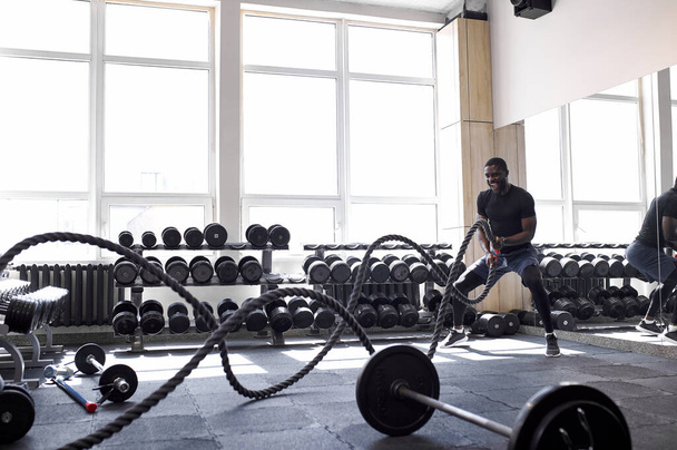 black athlete doing battle rope exercise at crossfit gym - Foto, Imagem