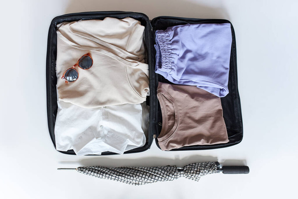 open suitcase with female clothes for trip on white background - 写真・画像