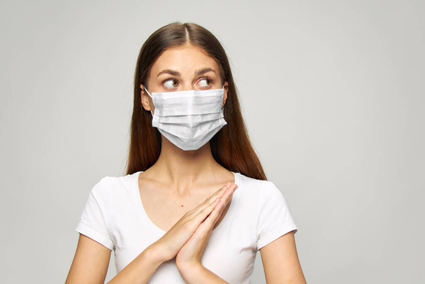Chica máscara médica en la cara, mira a los lados camiseta blanca  - Foto, Imagen