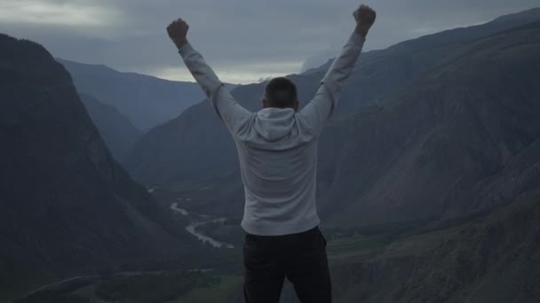 Hombre con las manos extendidas en la cima de una montaña - Imágenes, Vídeo