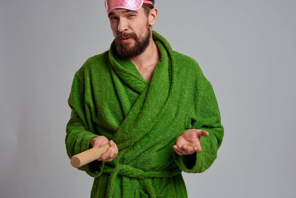 man with rolling pin in hand green robe pink sleep mask cropped view - Photo, Image