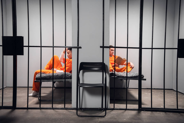 Les prisonniers dans leurs cellules s'ennuient avant que les lumières s'éteignent en prison. Lire des livres. Composition symétrique. Espace de copie - Photo, image
