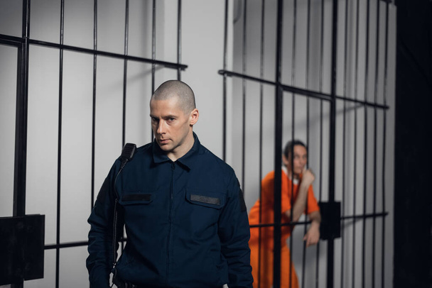 Ein strenger Gefängniswärter in Uniform bewacht Zellen mit Gefangenen in einem Hochsicherheitsgefängnis. - Foto, Bild