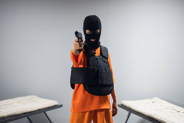 マスクと防弾チョッキ銃を持った少女が刑務所から逃げ出す - 写真・画像