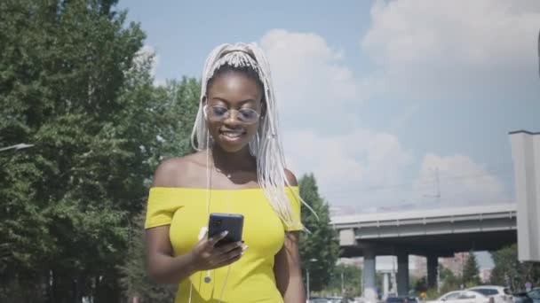 Nero femminile che indossa auricolari all'aperto - Filmati, video