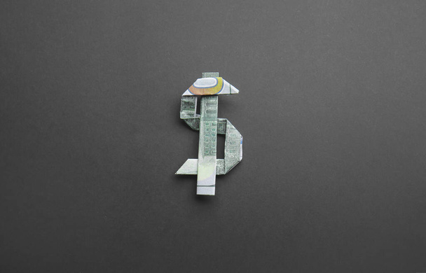 Фигура оригами из долларовых банкнот на тёмном фоне - Фото, изображение