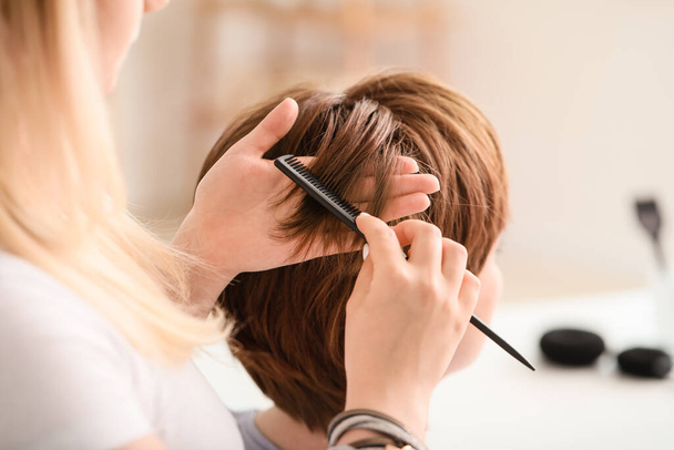 Профессиональный парикмахер работает с молодой женщиной в салоне красоты - Фото, изображение
