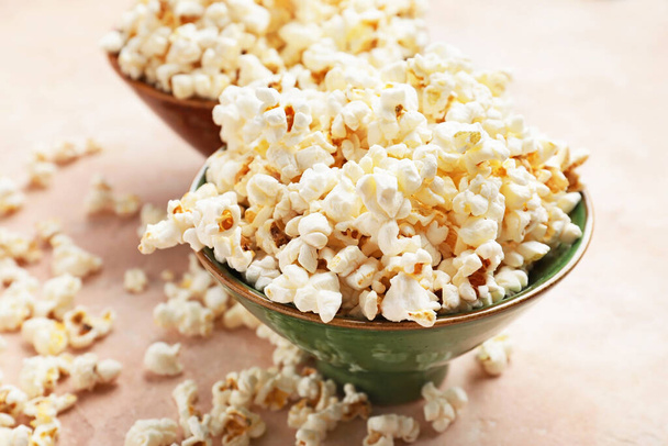 Bowl of tasty popcorn on color background - Фото, изображение