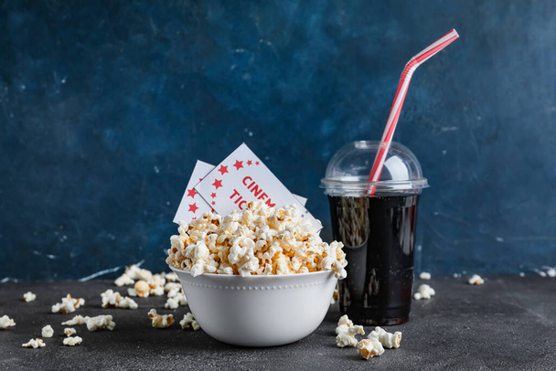 Schüssel leckeres Popcorn mit Kinokarten und Cola auf dunklem Hintergrund - Foto, Bild