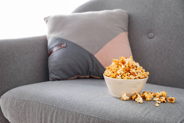 Bowl of tasty popcorn on sofa at home - Foto, afbeelding