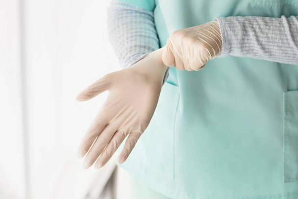 Doctor putting on medical gloves in clinic - 写真・画像