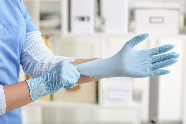 Doctor putting on medical gloves in clinic - 写真・画像