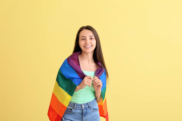 Young woman with LGBT flag on color background - Foto, imagen