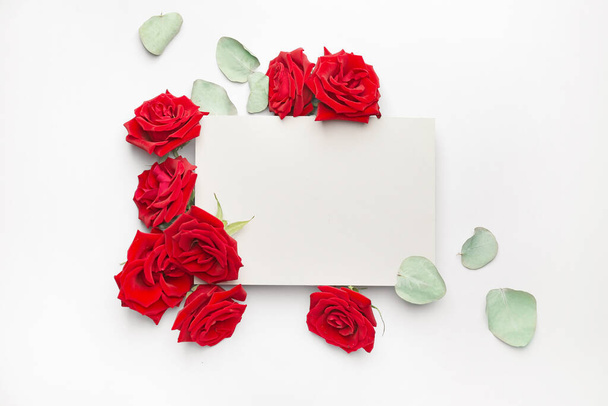 Beautiful red roses and blank card on white background - Fotó, kép