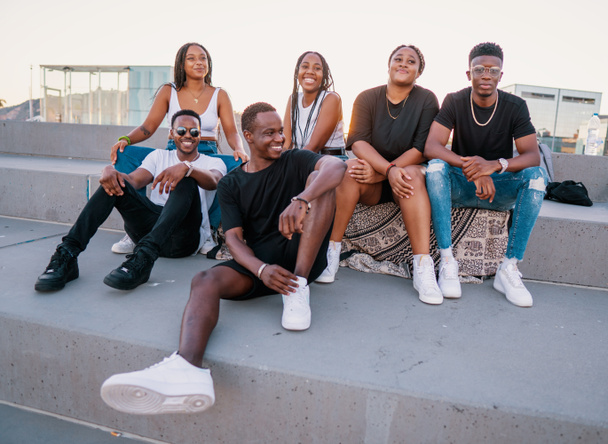 Gruppo di giovani amici neri africani moderni felicemente seduti insieme - Foto, immagini