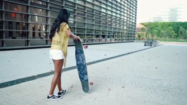 chica bastante atlética monta un longboard en la ciudad moderna - Metraje, vídeo