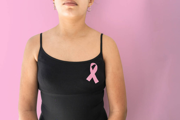 Detalle de la mujer en blusa negra con cinta de conocimiento de cáncer de mama y espacio de copia sobre fondo rosa. Atención ginecológica - Foto, imagen