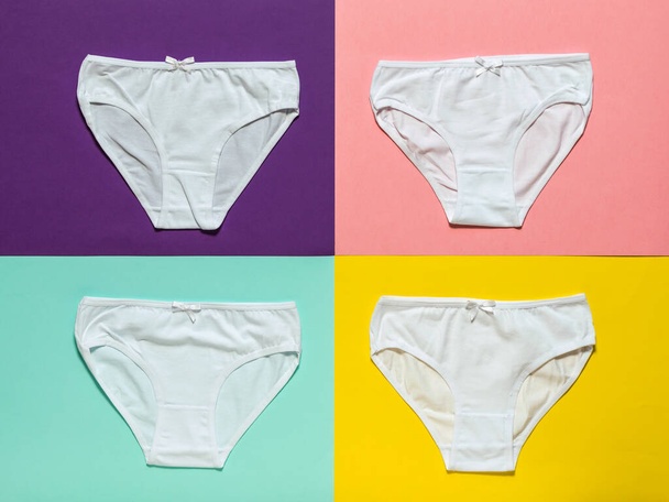 Set of four white women's panties on a multi-colored background. Flat lay. - Photo, Image