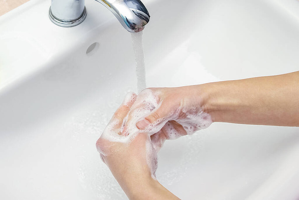 Hands with soap are washed under the tap with water. Clean from infection and dirt and virus. At home or in the hospital ablution office. - Foto, Bild
