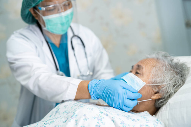 Aziatische arts dragen gezicht schild en PBM pak nieuwe normaal om de patiënt te controleren beschermen veiligheid infectie Covid-19 Coronavirus uitbraak in quarantaine verpleeghuis afdeling. - Foto, afbeelding