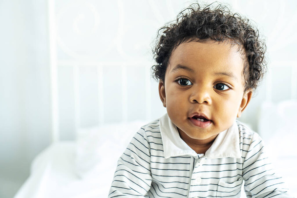 Adorable bébé africain aux cheveux moelleux debout sur le lit, Joli garçon - Photo, image