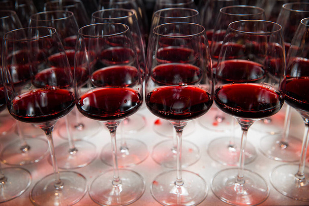 Er liggen glazen rode wijn op tafel, klaar om te serveren.. - Foto, afbeelding